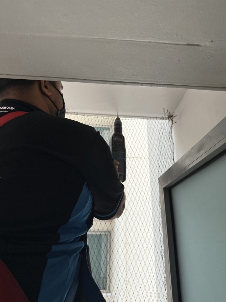UV-stabilised HDPE bird netting professionally installed on HDB aircon ledge in Singapore by Coogle Aircon — black mesh fully covering outdoor condenser unit