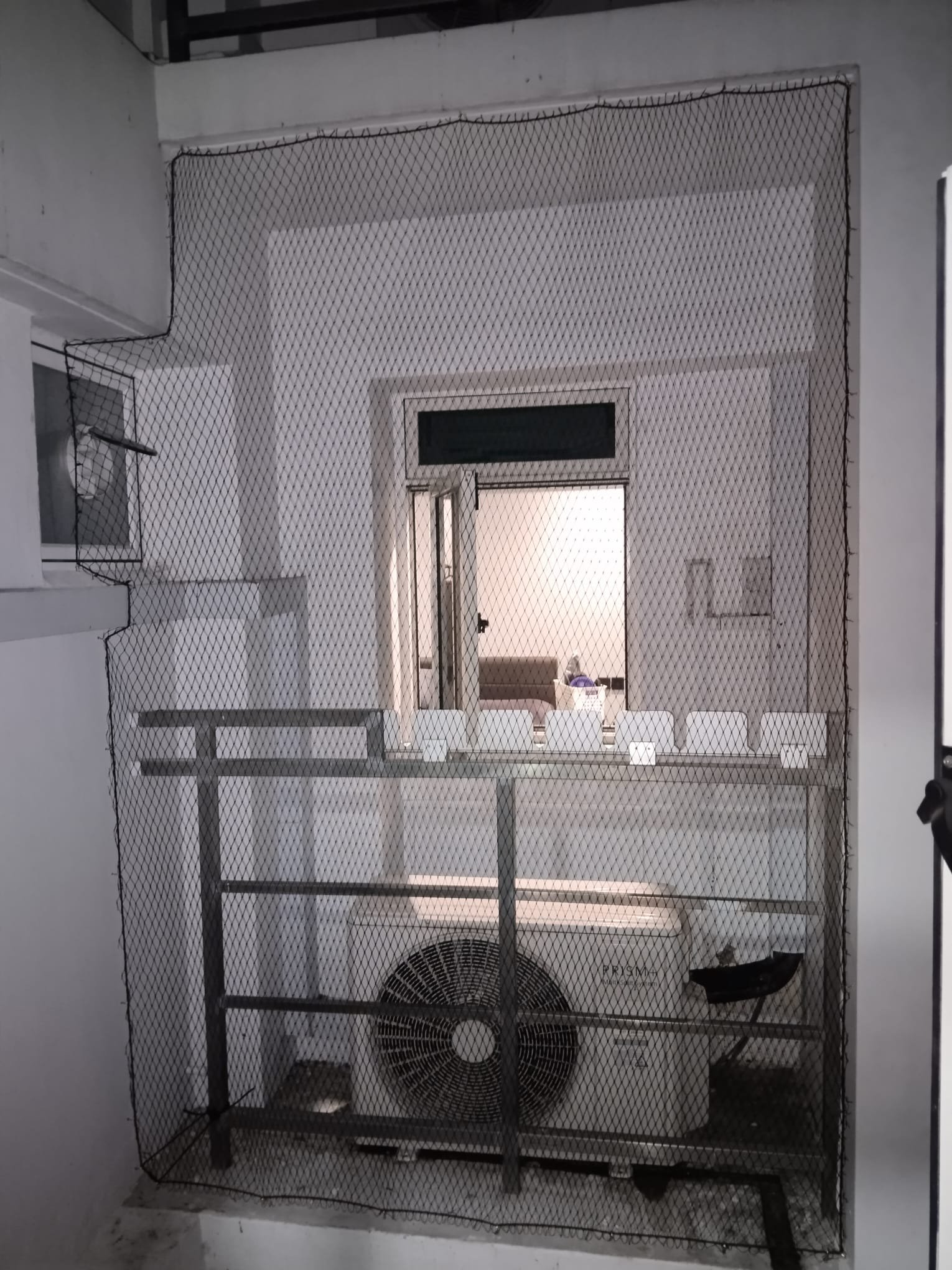 HDPE bird netting installed on HDB aircon ledge in Singapore — black soft-weave mesh covering outdoor condenser unit and service area